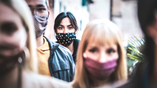 Commuter crowd of people moving on city street covered by face mask - New normal human condition and society concept - Focus on middle woman wearing black face mask - Desaturated contrast filter