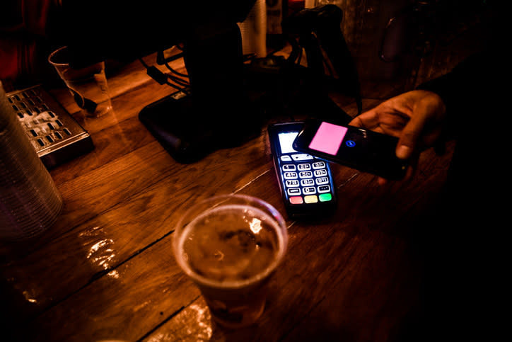 someone using their cell phone to pay for a drink