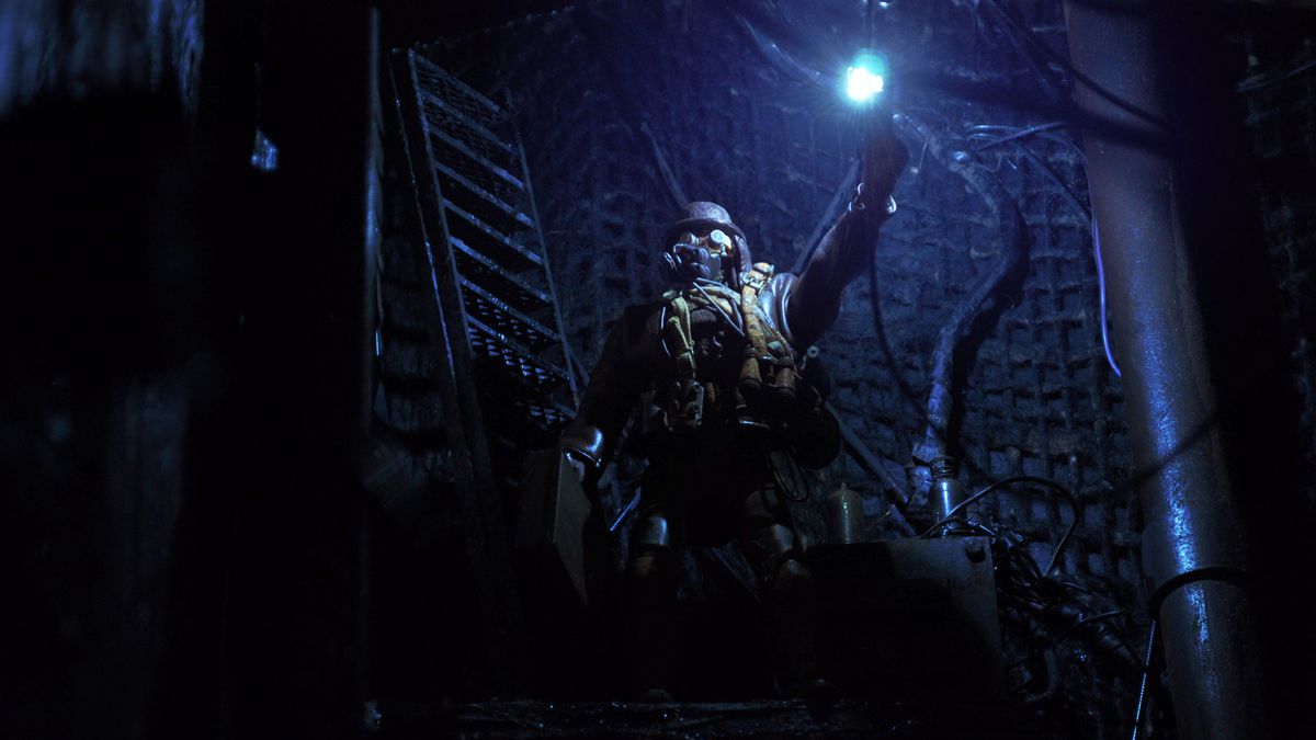 An assassin in a gas mask holds a light in a dark underground corridor in Mad God.