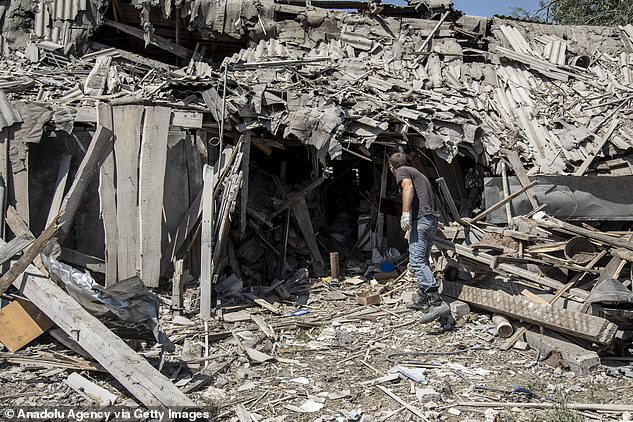 A man collects his belongings from his house in Siversk, near Donetsk, which was hit by rockets