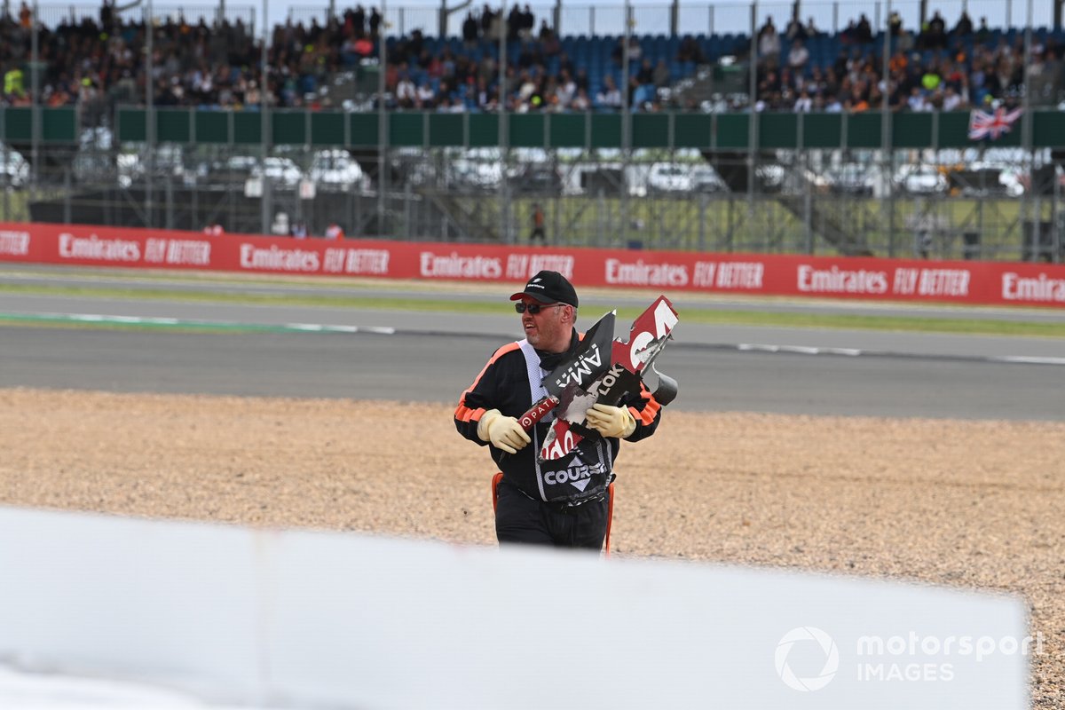 A marshal collects debris after the crash on the first lap