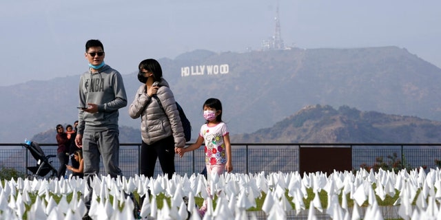 Visitors walk past a memorial to victims of COVID-19 at the Griffith Observatory on Friday, November 19, 2021 in Los Angeles.  Thousands of flags were placed on the lawn in front of the observatory to commemorate those who died from COVID-19 in Los Angeles County on November 2. 