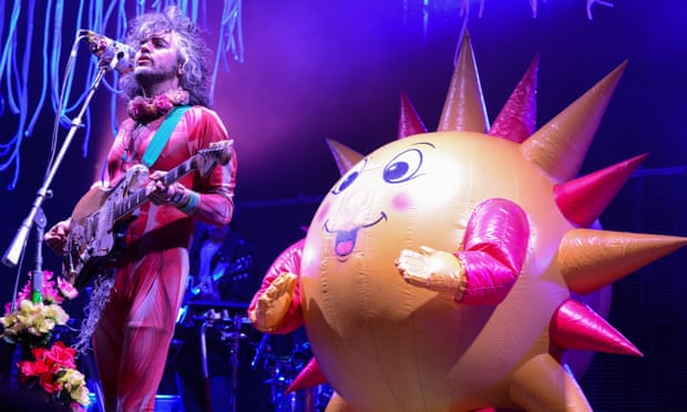 A giant, spiky balloon with a happy face joins Coyne on stage