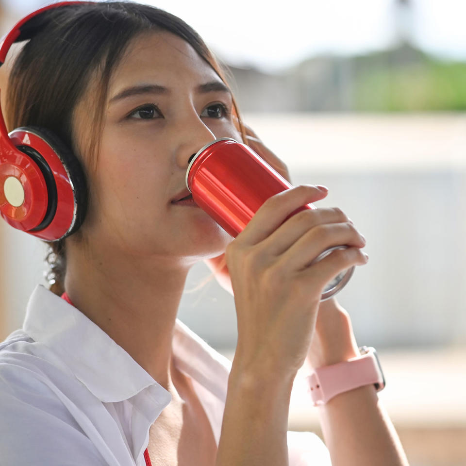 Woman with headphones drinking energy drink